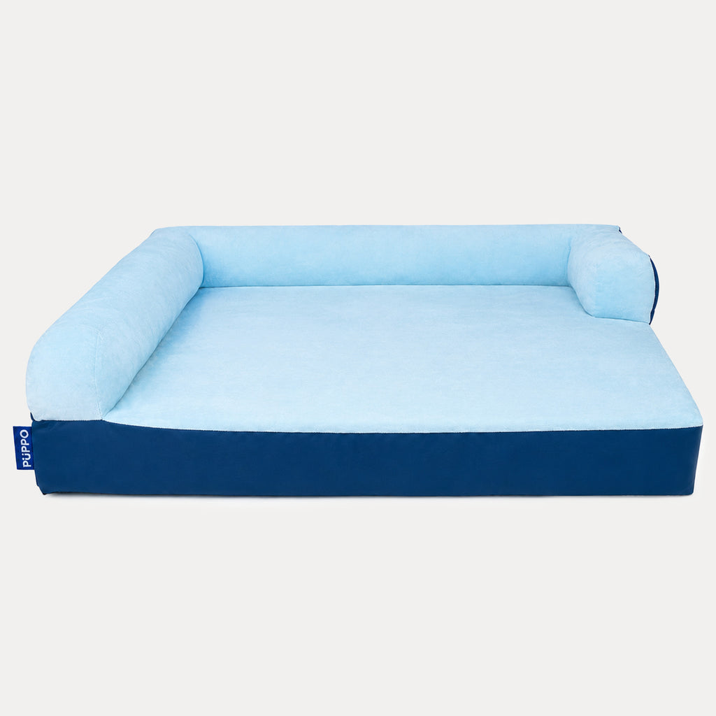 A rectangular pet bed with a light blue cushioned top and backrest, and a dark navy blue base, shown on a plain light gray background.